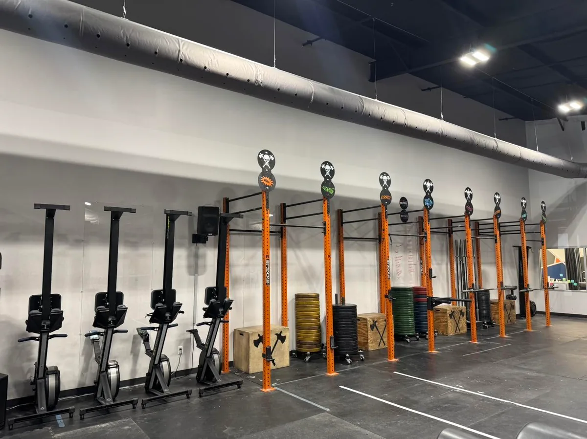 The Bluff City Performance training floor with Concept2 SkiErgs, the orange pull-up rig and plate storage